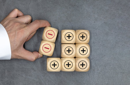 Plus and minus icons on wooden cubes. Separate the negative from positive, removing the weaknesses...