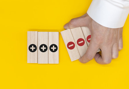 Plus and minus icons on wooden cubes. Separate the negative from positive, removing the weaknesses...