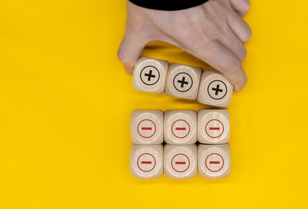 Plus and minus icons on wooden cubes. Separate the negative from positive, removing the weaknesses...
