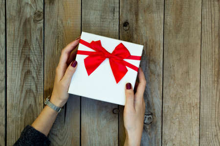 Woman holding a gift box on wooden table.