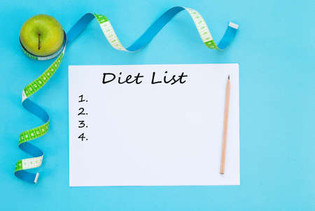 Fresh apple, measuring tape, and diet list on blue background.