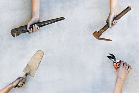 Hands holding construction tools on gray background.の写真素材