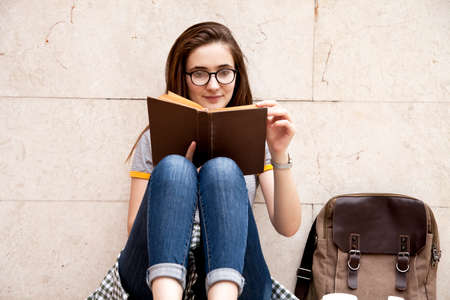 Young student female reading book in outdoors.の写真素材