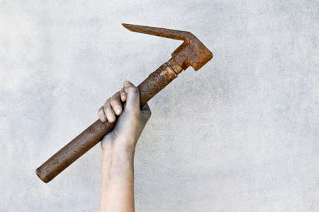Hand holding old rusty hammer on gray background.の写真素材