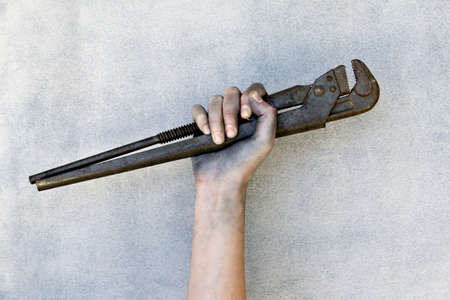 Hand holding a adjustable wrench isolated on gray background.の写真素材