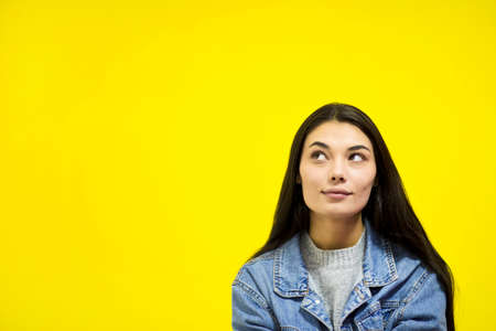 Young beautiful woman looking away at copy space isolated on yellow background.の写真素材
