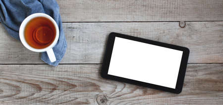 Cup of tea and digital tablet on wooden table.の写真素材
