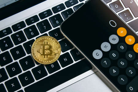 Close-up of bitcoin and phone calculator on the computer keyboardの写真素材