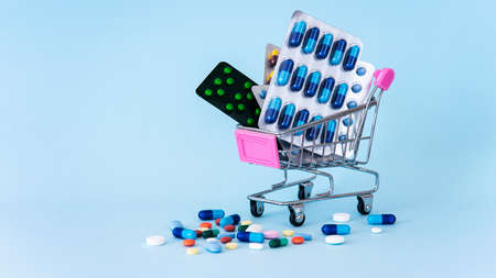 Pills in a shopping cart on a blue backgroundの写真素材