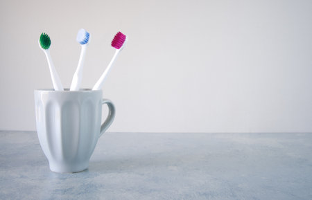 Colorful toothbrushes in a glass on the tableの写真素材