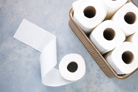 Toilet paper rolls in wicker basket on grey table