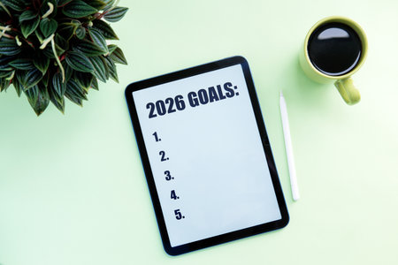 2026 GOAL with digital tablet, coffee cup and pen on light green background.の写真素材