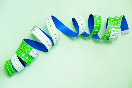 Tape measure on a light green background.の写真素材