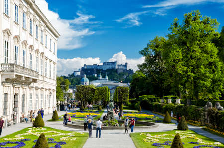 Salzburg, Austria - May 7, 2016: Beautiful view of Mirabell Gadens in Salzburg. Spring blooming flowerbeds, green trees, people walking through the alleys. Fortress Hohensalzburg in the background.のeditorial素材
