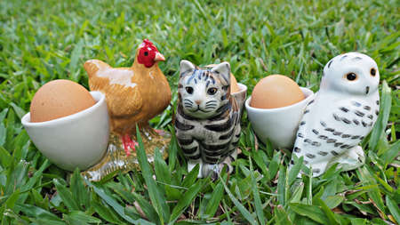Eggs in cute  ceramic animal egg cups on grass. Easter background.