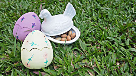 Easter eggs with white ceramic chicken on grass. Painted eggs.の写真素材