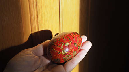 Colorful Easter egg in woman hand with light and shadow.の写真素材