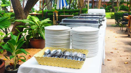 Preparing Buffet table with food trays, dishes, spoons and forks for lunch party.の写真素材