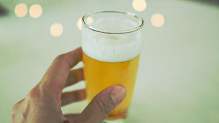 Hand holding glass of beer with white background.の写真素材