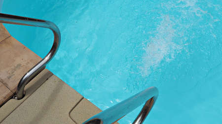 Clear and clean water in swimming pool. Stainless steel handrails and swimming pool background.の写真素材
