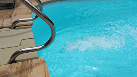 Clear and clean water in swimming pool. Stainless steel handrails and swimming pool background.の写真素材