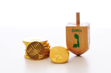 Hanukkah dreidel standing on end next to Hanukkah gelt candy set against a white background.の写真素材