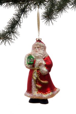Santa Claus ornament hanging from a pine bough set against a white background.の写真素材