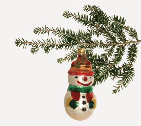 Snowman Christmas decoration hanging on a pine bough set against a white backgroundの写真素材