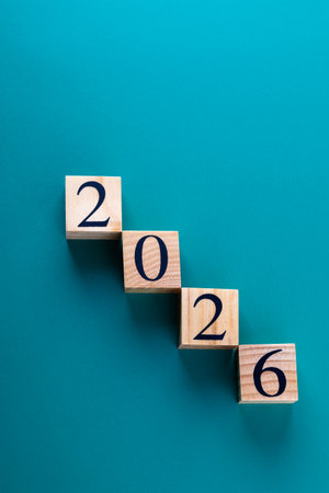 Vertical shot of wooden cubes arranged in a descending staircase forming 2026 on blue background....