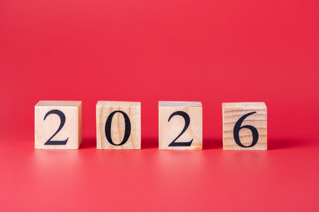 Wooden cubes aligned with number 2026 on bright red background, clear and minimalist horizontal...