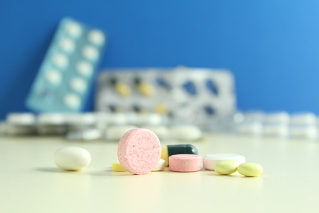 Capsule pills medical, white and pink, on a blue background.