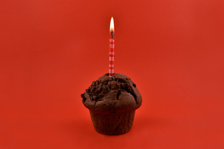 Muffin with candle stock images. Chocolate muffin with heart on a red background. Sweet birthday pastry. Valentines Day conceptの写真素材