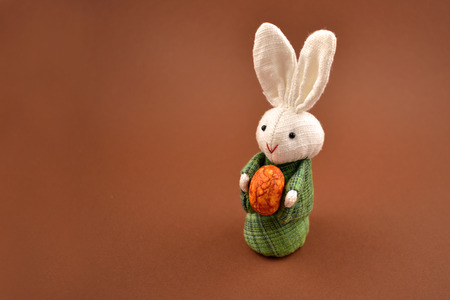 White rabbit toy stock images. Easter bunny on a brown background. Easter rabbit with egg. Spring decoration images. Easter conceptの写真素材