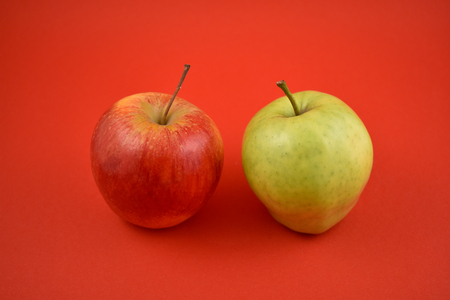 Red and green apple stock images. Apples on a red background. Two ripe apples. Red and green apples isolated on a colorful backgroundの写真素材
