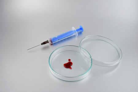Petri dish with blood stock images. Petri dish with a blood on a gray background. Laboratory accessories. Injection and petri dishの写真素材