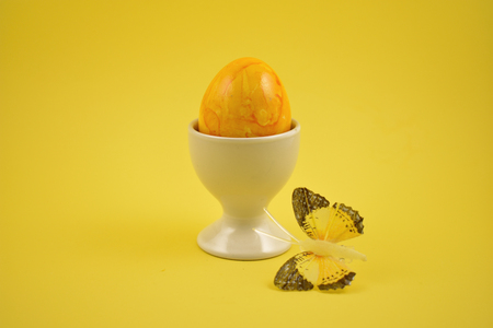 Yellow decorated easter egg stock images. Spring decoration images. Ceramic egg stand with yellow egg. Easter decoration on a yellow backgroundの写真素材