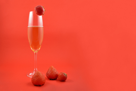 Glass of champagne with strawberries stock images. Strawberries with champagne. Champagne on a red background with copy space for text. Festive red background. Valentines Day conceptの写真素材