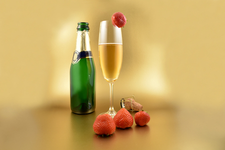 Glass of champagne with strawberries stock images. Champagne on a golden background with copy space for text. Festive golden background. Valentines Day conceptの写真素材