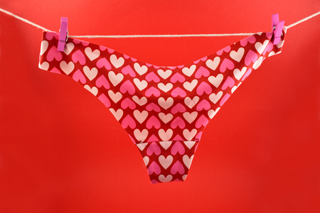 Pink panties with hearts stock images. Valentines Day concept. Panties on a red background. Women's panties on the clotheslineの写真素材