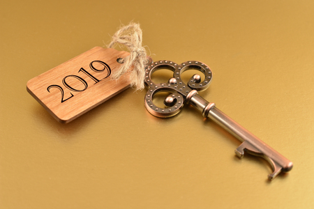 Key to the New Year 2019. Old key with wooden tag. Decorated key isolated on a white background. Romantic key with wooden label. Golden New Year 2019の写真素材