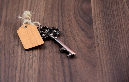 Decorative metal key stock images. Decorated key isolated on a wooden background. Romantic key with wooden label. Vintage key on the tableの写真素材
