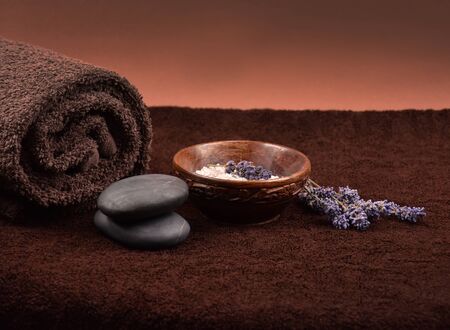 Spa setting on brown background stock images. Wellness background. Spa still life images. Bath salt in bowl, lava stones and lavender on brown textured backgroundの写真素材