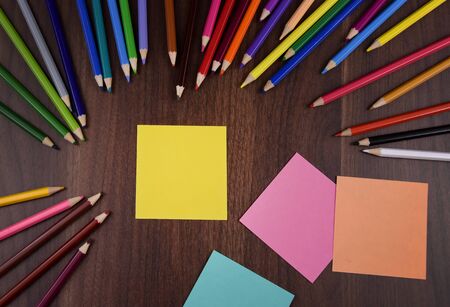 Yellow stick note paper on the table stock images. Crayons on wooden background. Set of colored...
