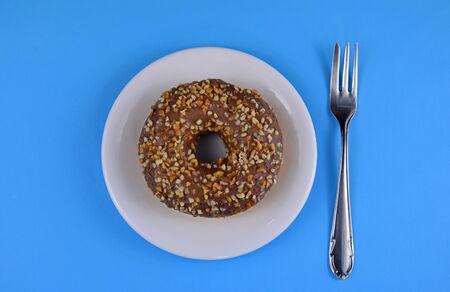 Chocolate donut on a plate top view stock images. Donut isolated on a blue background. Donut with chocolate frosting and nuts stock imagesの写真素材