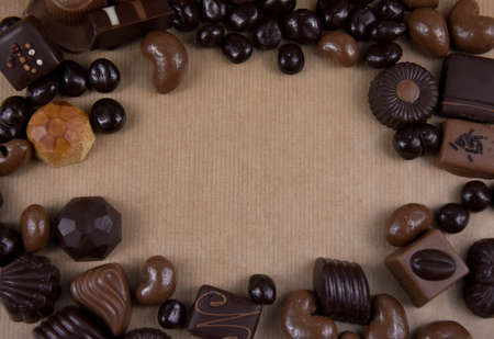 Chocolate pralines frame top view stock images. Chocolate candies on a brown background. Chocolate...