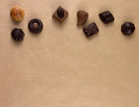 Chocolate pralines frame top view stock images. Chocolate candies on a brown background. Chocolate...