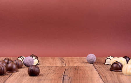 Chocolate pralines on a wooden background frame stock images. Different types of chocolate candies...