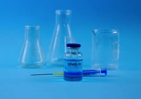 COVID-19 vaccine with syringe stock images. Coronavirus vaccine and injection isolated on a blue...