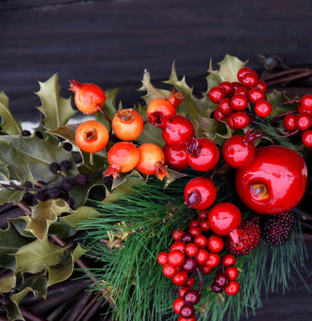 Beautiful winter decoration with red fruit and berries stock images. Natural winter holiday red decoration on a wooden background. Beautiful Christmas arrangement close-upの写真素材