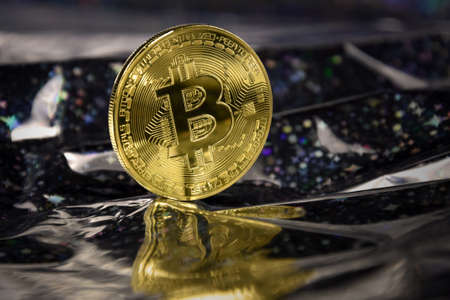 One bitcoin golden coin stock images. Cryptocurrency on a shiny dark background. Digital gold images. Beautiful gold bitcoin coin photo imagesの写真素材